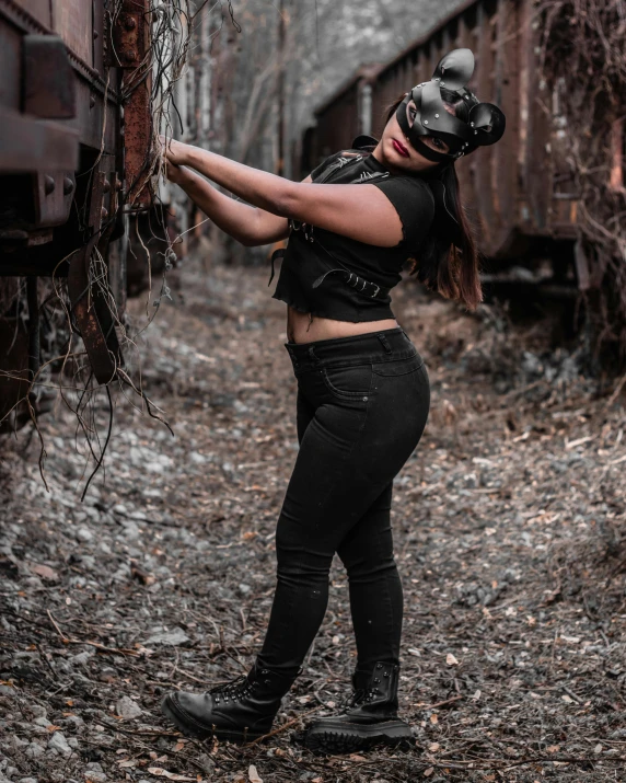 a woman wearing a mask standing next to a train, an album cover, pexels contest winner, black extremely tight jeans, post apocalyptic attire, profile picture 1024px, thicc