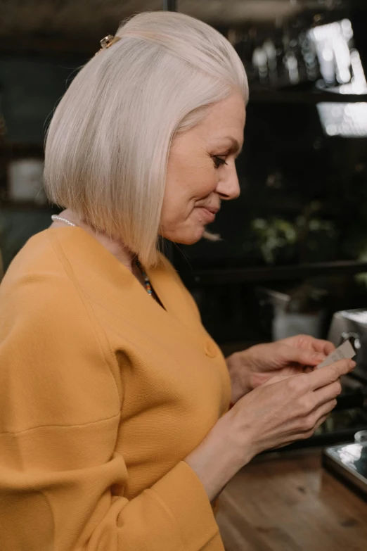 a woman using a smart phone in a kitchen, a portrait, by Adam Marczyński, pexels contest winner, white-haired, holding gold watch, profile image, gif