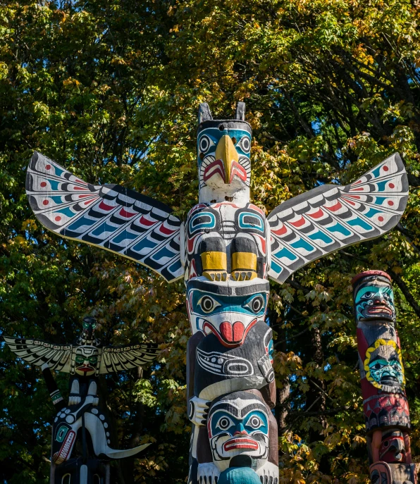 a group of totem poles in front of a tree, pexels contest winner, looking like a bird, vancouver, fall season, avatar image