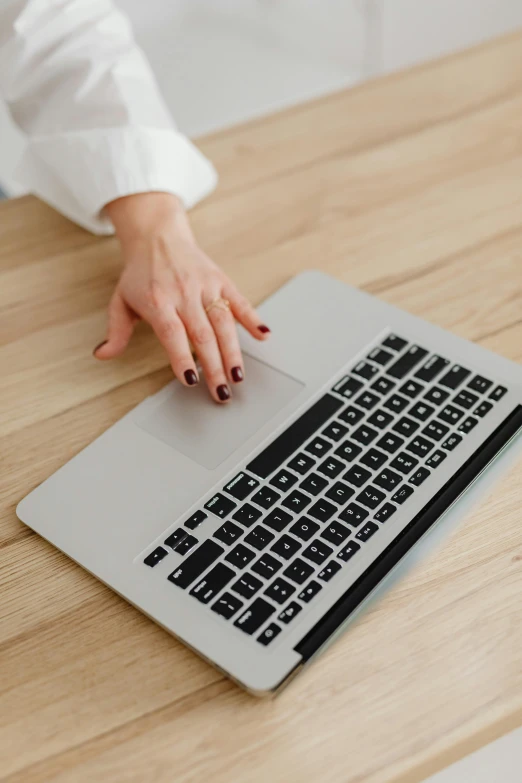 a close up of a person typing on a laptop, wearing business casual dress, on a wooden desk, profile image, maintenance