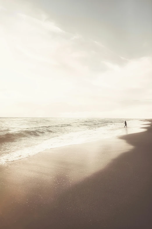 a person walking on a beach next to the ocean, by Andries Stock, sunfaded, 8 k photo, soft light - n 9, 4k)