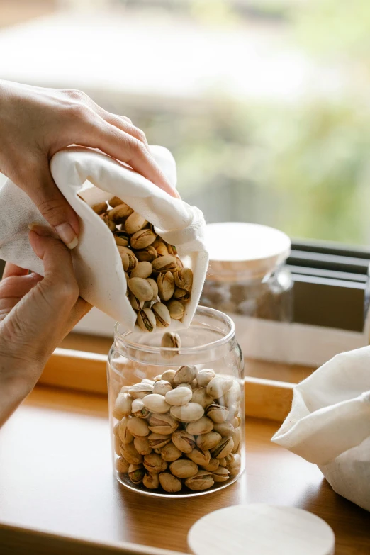 a person putting nuts in a jar on a window sill, by Julia Pishtar, soft volume absorbation, beans, japanese, white