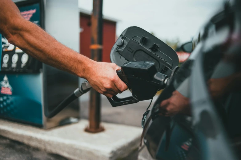 a person pumping gas into a car at a gas station, pexels contest winner, square, avatar image, brown, 268435456k film