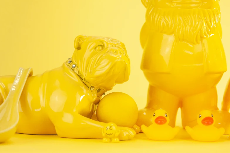 a group of yellow figurines sitting next to each other, a statue, inspired by Jeff Koons, trending on cg society, pug, made of wax and water, detailed product image, monochromatic