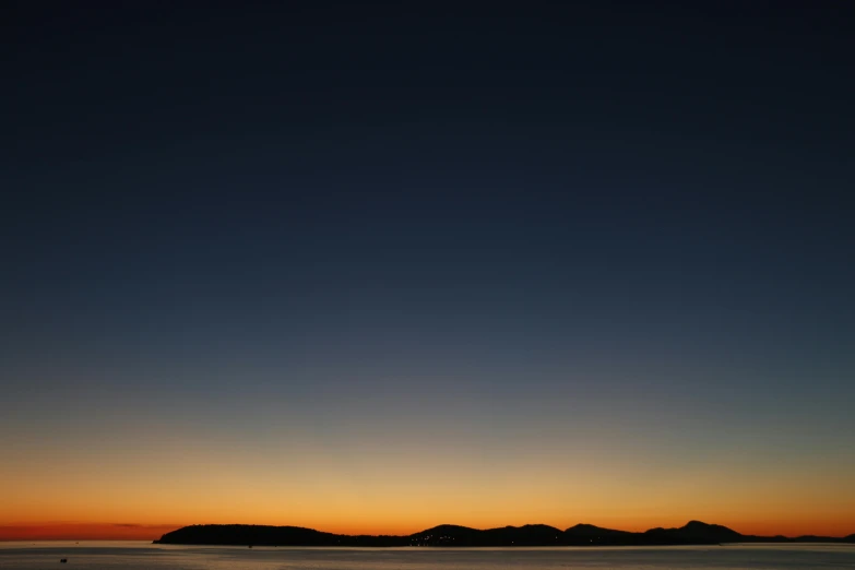 the sun is setting over a body of water, by Doug Ohlson, minimalism, night time photograph, dark blue + dark orange, cloudless-crear-sky, color ( sony a 7 r iv