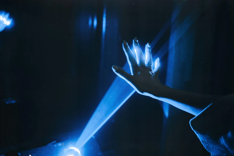 a close up of a person holding a light, unsplash, holography, 1 9 8 5 photograph, hands reaching for her, blue, cinema lighting