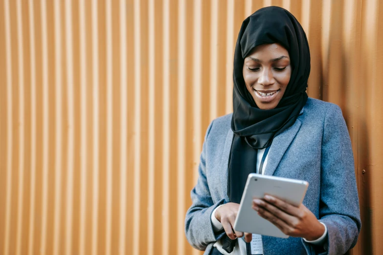 a woman in a hijab using a tablet, by Carey Morris, trending on unsplash, fan favorite, rectangle, avatar image, standing sideways