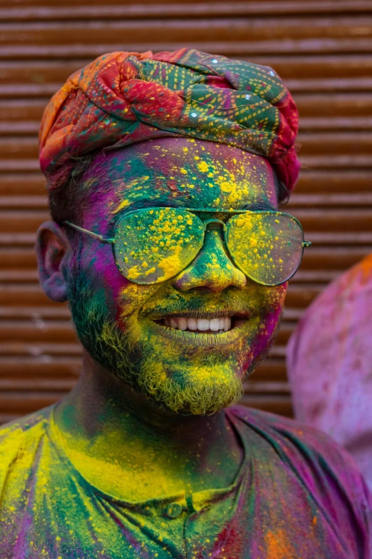 a man with paint all over his face, pexels contest winner, color field, wearing shades, on an indian street, smiling for the camera, rich iridescent colors