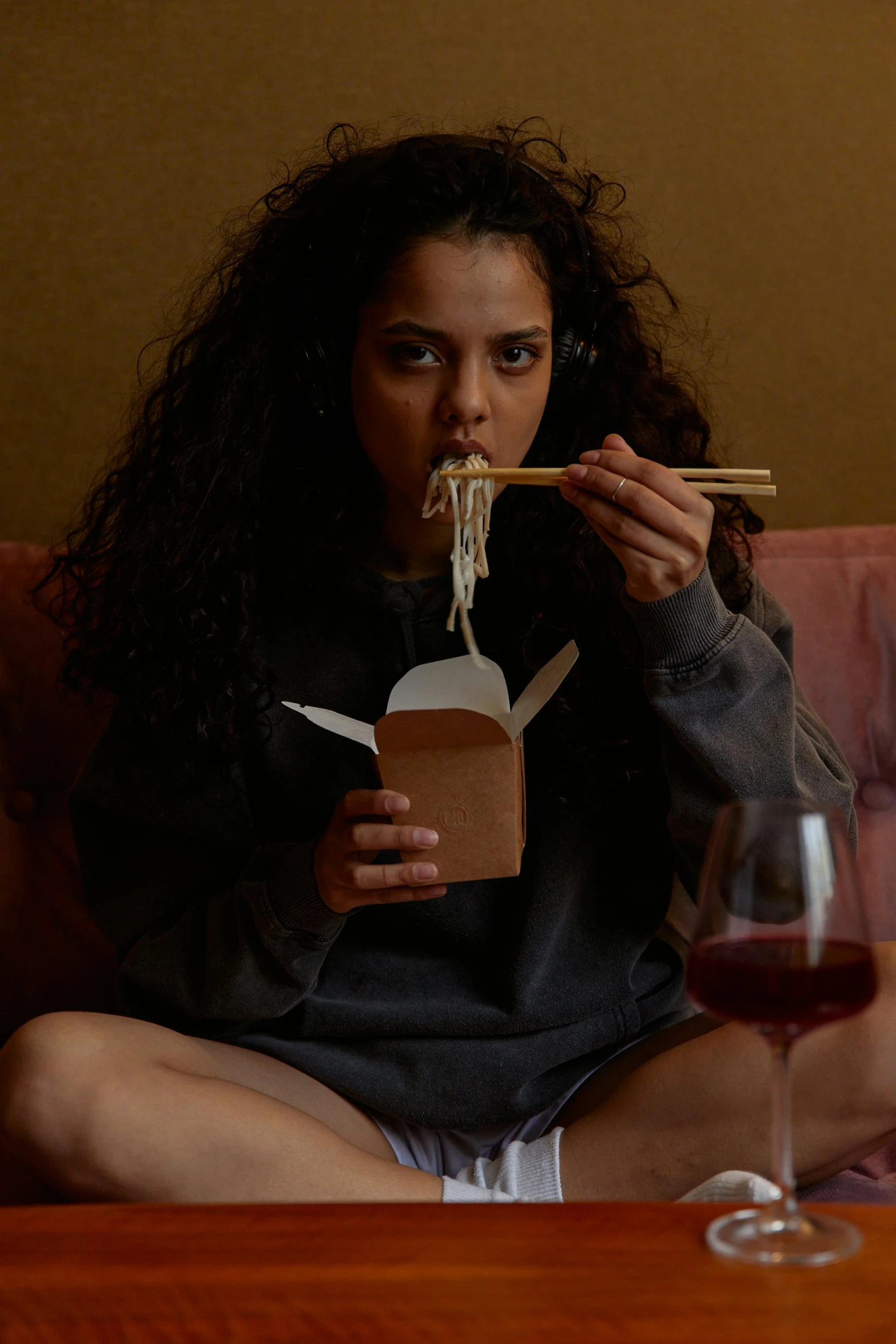 a woman sitting on a couch eating noodles with chopsticks, by Adriaen Hanneman, instagram, nathalie emmanuel, filmstill, alessio albi, booze