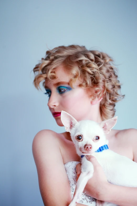 a woman holding a small white dog in her arms, an album cover, inspired by Cindy Sherman, trending on reddit, short curly blonde haired girl, she has pale blue skin!!!, portrait shot 8 k, young beautiful amouranth