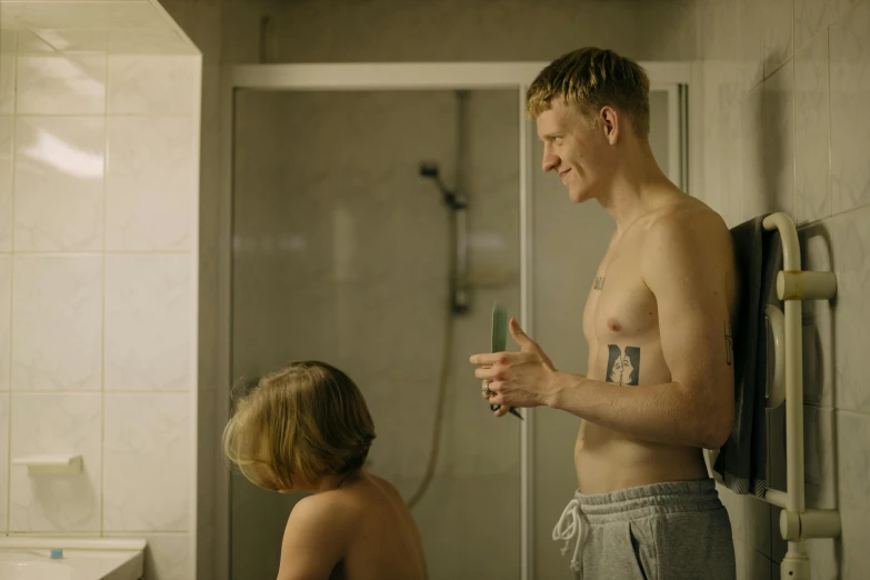 a man standing next to a child in a bathroom, a tattoo, by Jaakko Mattila, happening, movie still, vitalik buterin, romance, thumbnail