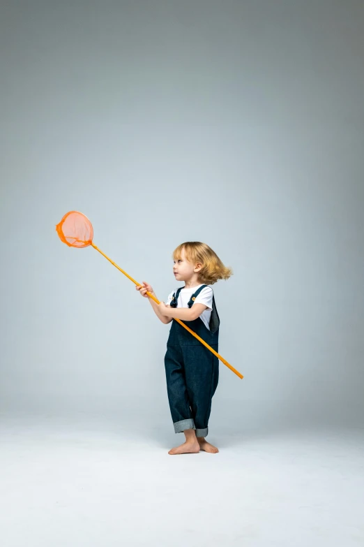 a little girl that is holding a net, by Paul Bird, plain background, antennae, wearing overalls, goldfish