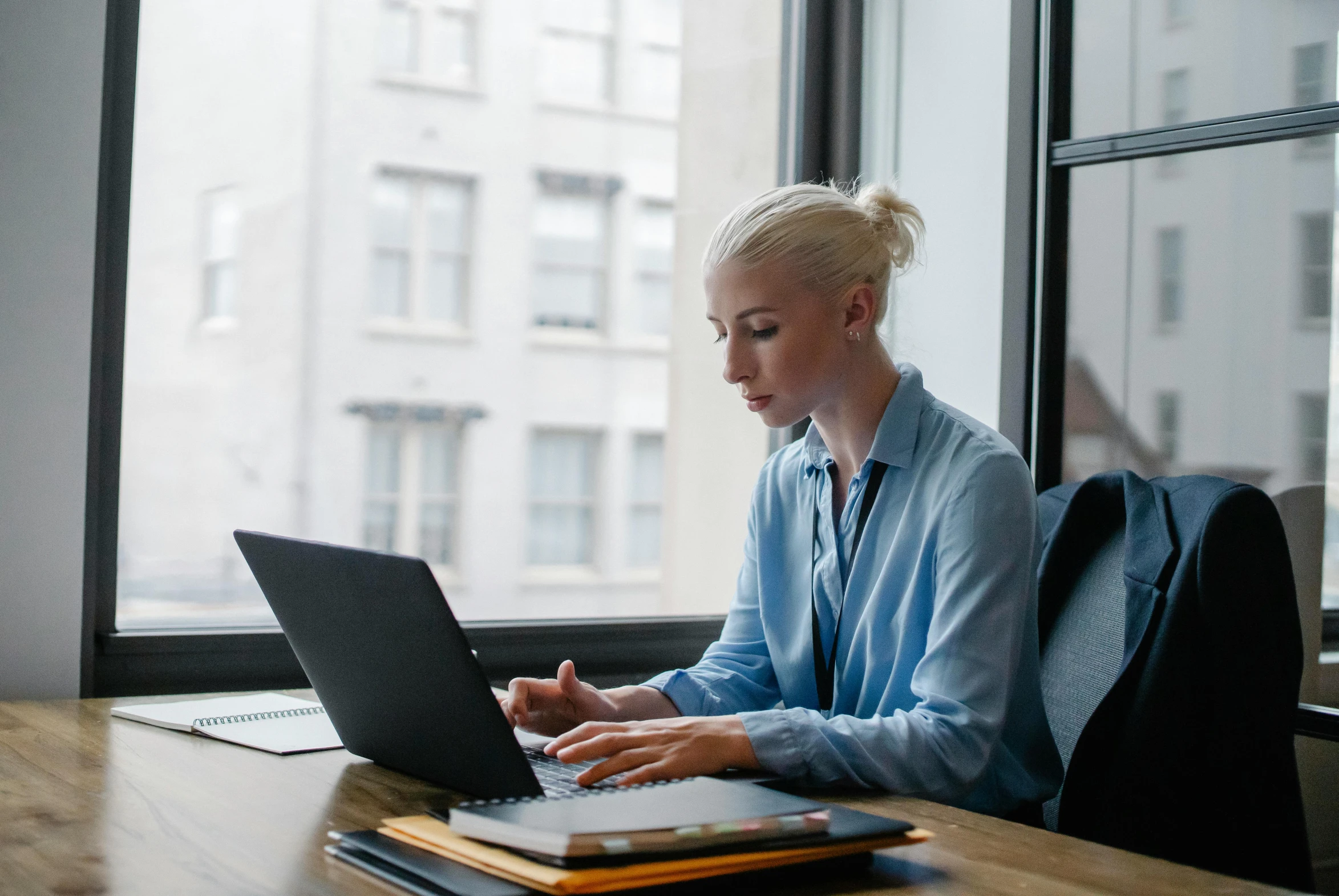 a woman sitting at a table using a laptop computer, pexels contest winner, royal commission, female in office dress, a blond, non-binary