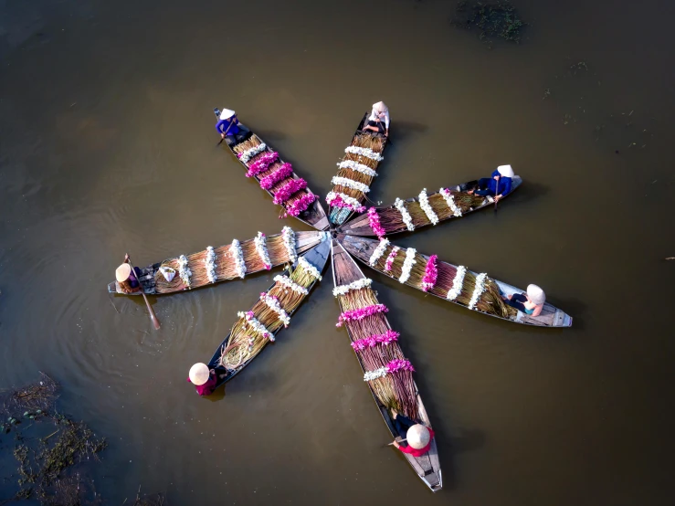 a group of boats floating on top of a body of water, by Ibrahim Kodra, pexels contest winner, land art, seven pointed pink star, tribals, floating bouquets, contest winner 2021