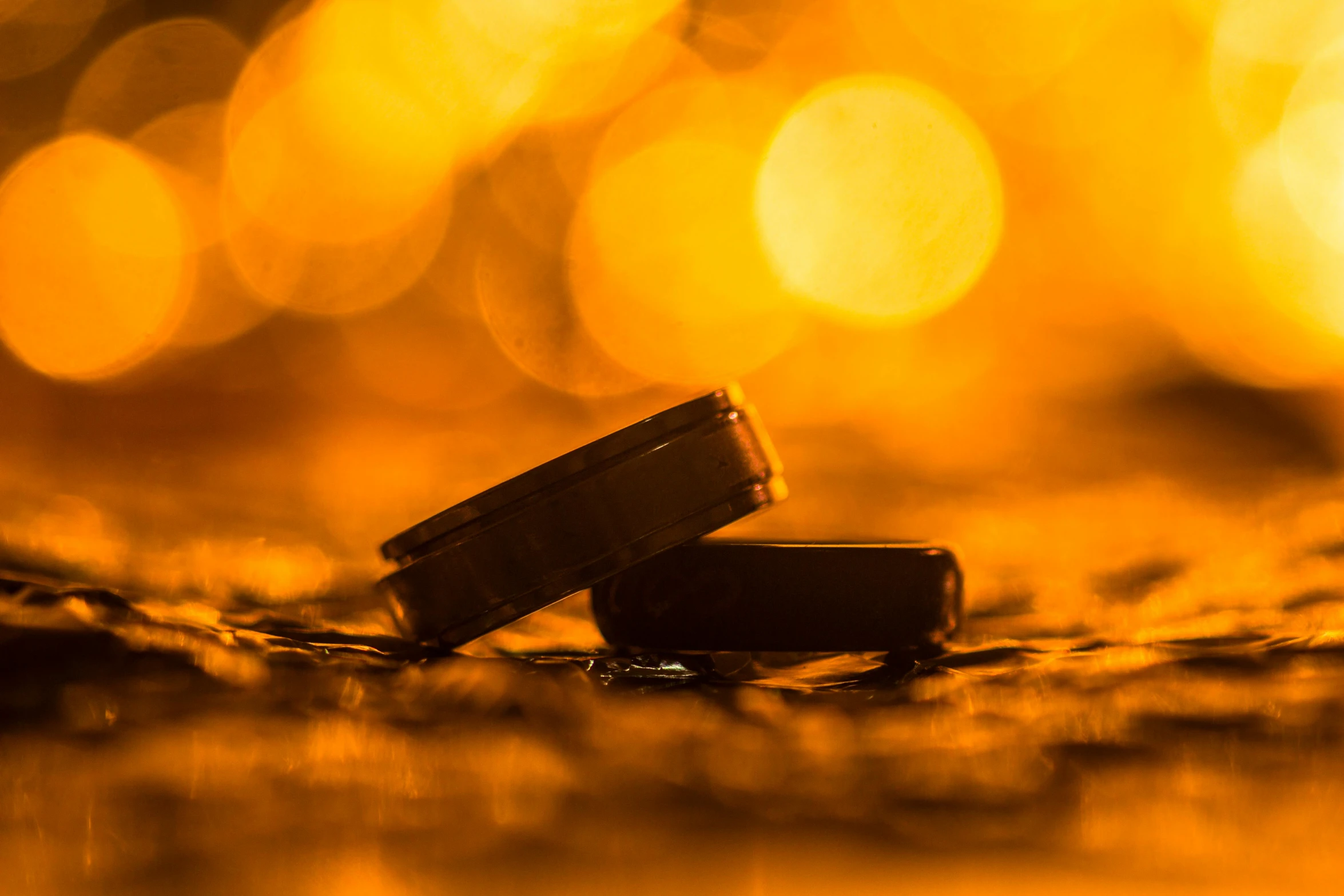 a couple of wedding rings sitting on top of a table, a macro photograph, by Niko Henrichon, unsplash, visual art, black and orange, warm golden backlit, slick tires, high quality product image”