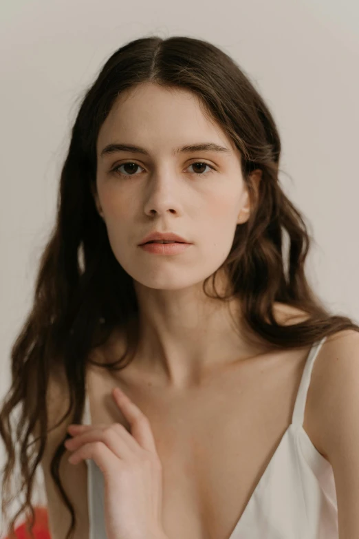 a woman in a white dress posing for a picture, a character portrait, trending on pexels, pale thin lips, wearing a camisole, brunette woman, skincare