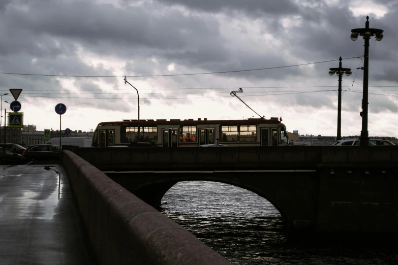 a train traveling over a bridge over a river, a portrait, by Ihor Podolchak, unsplash, modernism, gray clouds, street tram, 2000s photo, saint petersburg