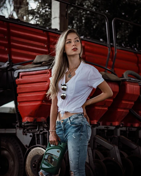 a woman standing in front of a red truck, a colorized photo, by Adam Marczyński, pexels contest winner, white shirt and jeans, wearing an ammo belt, bag over the waist, handsome girl