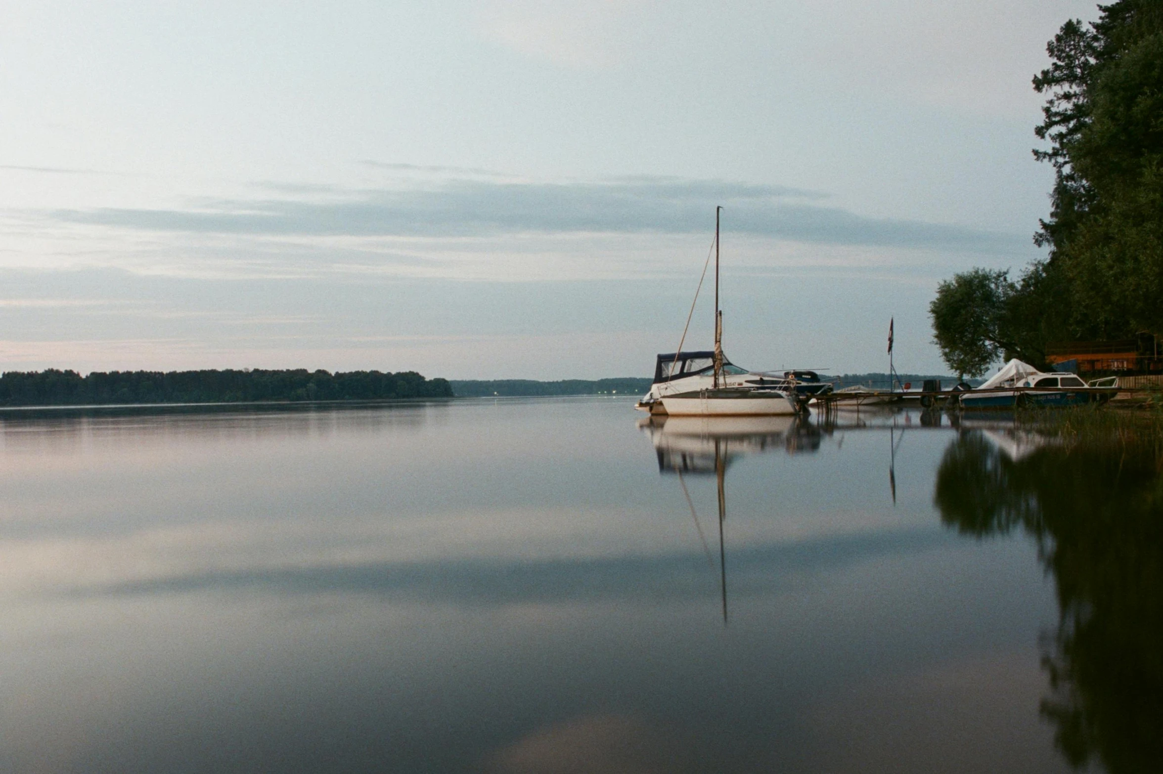 a couple of boats sitting on top of a lake, by Jan Tengnagel, pexels contest winner, bucklebury ferry, sailboat, calm evening, 2022 photograph