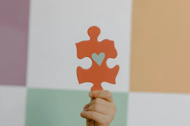 a person holding a piece of puzzle in their hand, by Emma Andijewska, trending on pexels, orange and cyan paint decals, cuddly, giant wooden club, compassion
