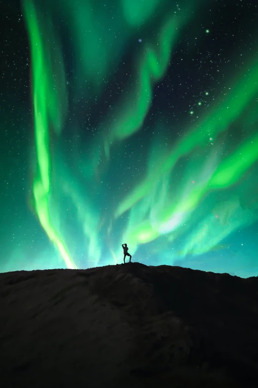 a person standing on top of a hill under the aurora lights, doing a majestic pose, nat geo, nordic, 8k resolution”