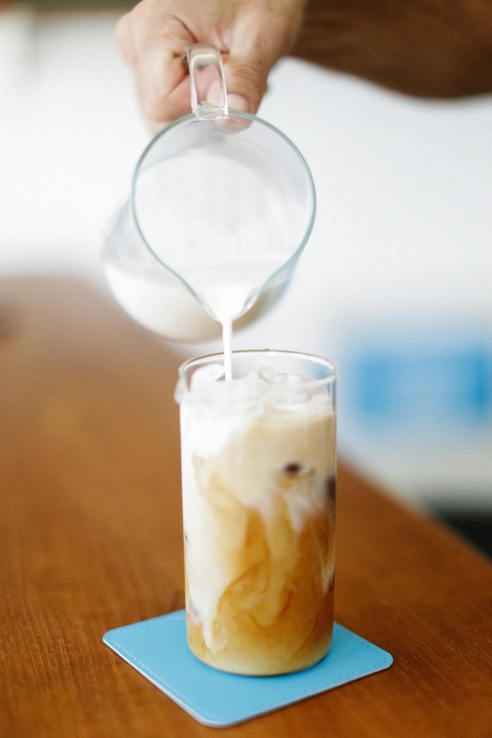 a person pours milk into a glass of iced coffee, by Arabella Rankin, unsplash, square, white, bao pham, made of glazed