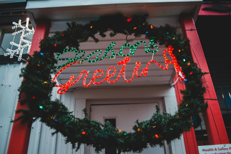 a christmas wreath hanging from the side of a building, pexels, graffiti, neon greek, arney fretag, warm street lights store front, profile image