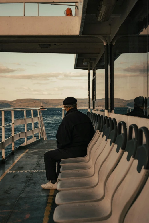 a man sitting on top of a boat next to the ocean, fading off into the distance, manly, inside a grand, looking old