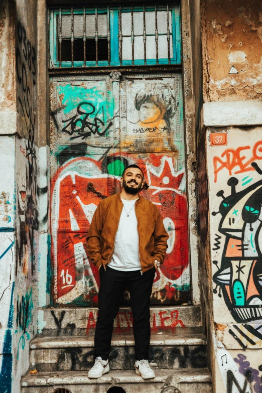 a man standing in front of a door covered in graffiti, an album cover, pexels contest winner, young greek man, 🚿🗝📝, juanmao, demna gvasalia