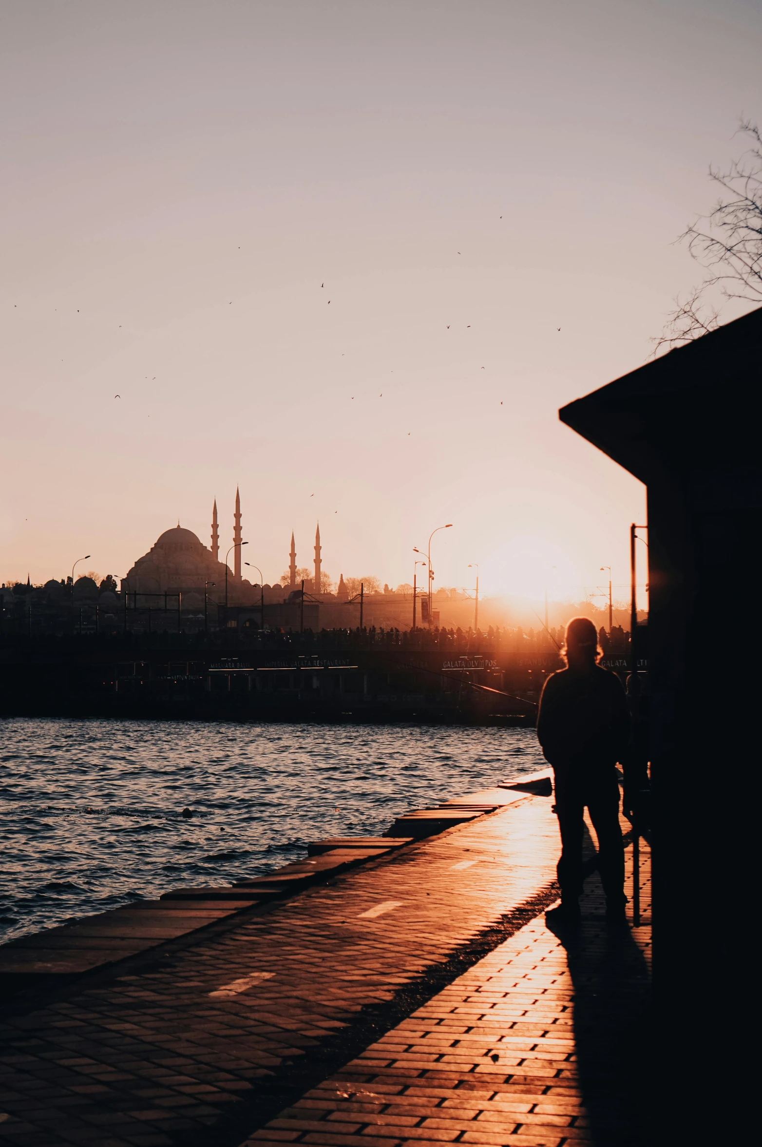 a couple of people standing next to a body of water, pexels contest winner, hurufiyya, istanbul, 256x256, winter sun, walking to the right