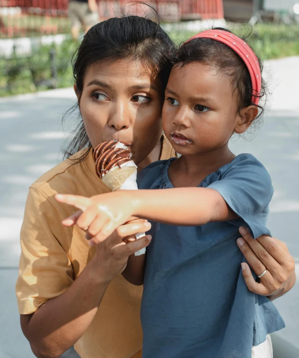 a woman holding a child and eating an ice cream cone, by Lily Delissa Joseph, pexels contest winner, conceptual art, south east asian with round face, movie still 8 k, production still, brown