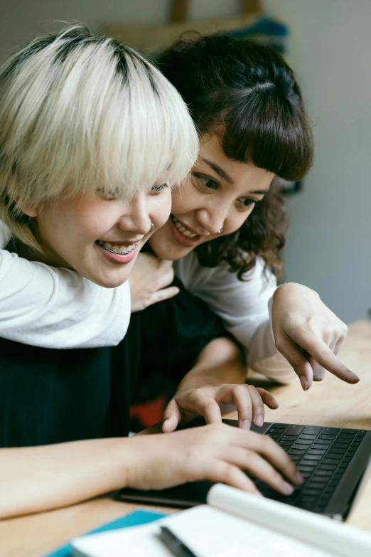 a couple of women sitting at a table with a laptop, trending on pexels, japan studio game, smiling playfully, zoomed in, avatar image