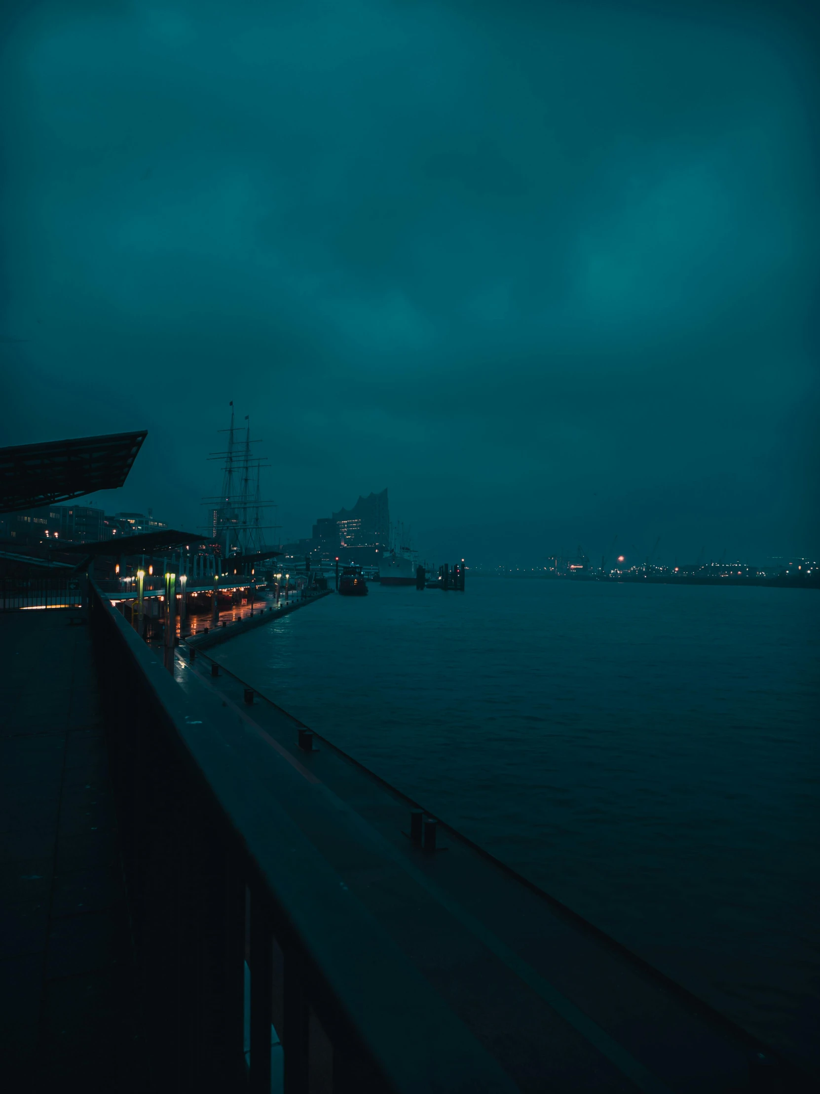 a view of a body of water at night, inspired by Elsa Bleda, happening, rainy and gloomy atmosphere, harbor, lightroom preset, cinematic shot ar 9:16 -n 6 -g