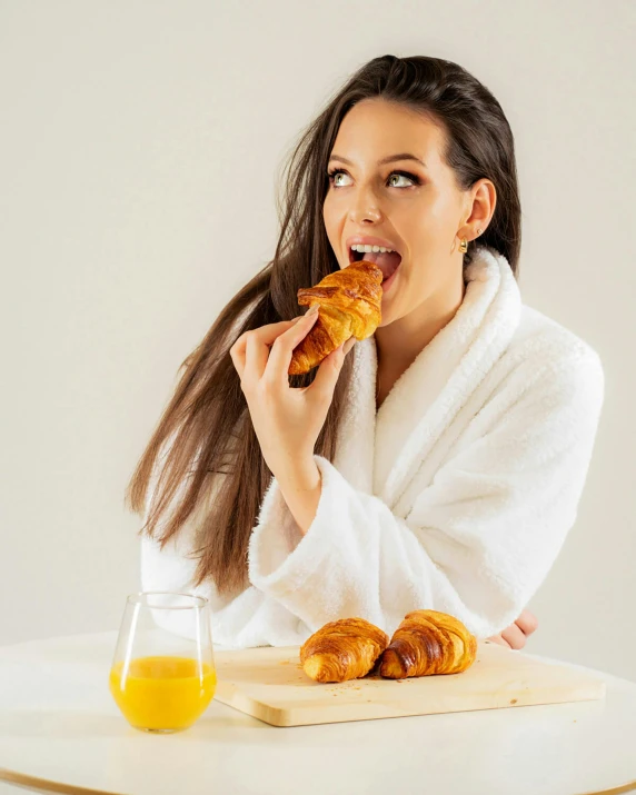 a woman sitting at a table eating croissants, pexels contest winner, happening, bathrobe, skincare, profile image, white background