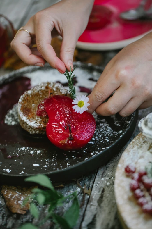 a close up of a plate of food on a table, by Lucia Peka, pexels contest winner, process art, holding a flower, desserts, red apple, digging