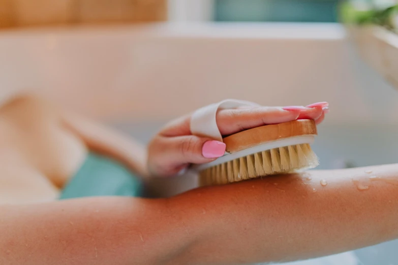 a close up of a person holding a brush in a bathtub, tachisme, with arms bare, tans, spa, family friendly