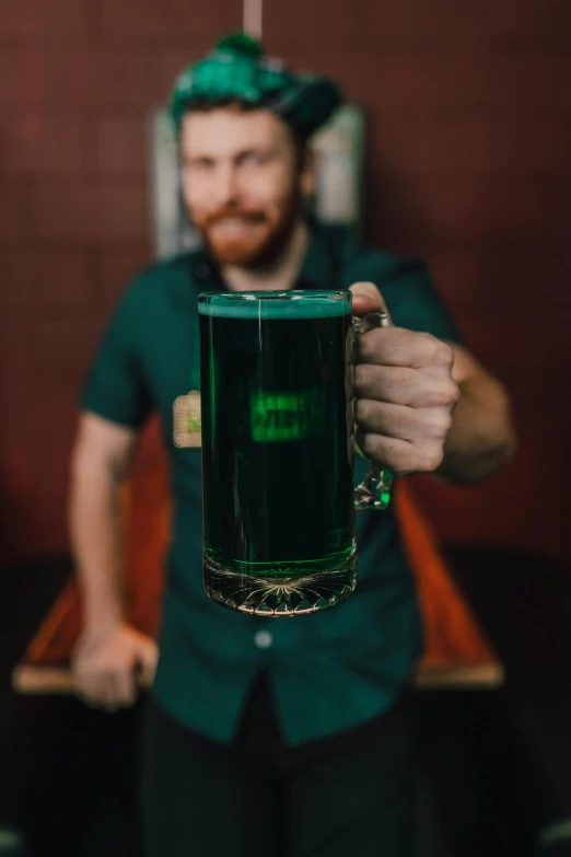 a man is holding a glass of beer, wearing green, bitches brew, dark blue and green tones, staff