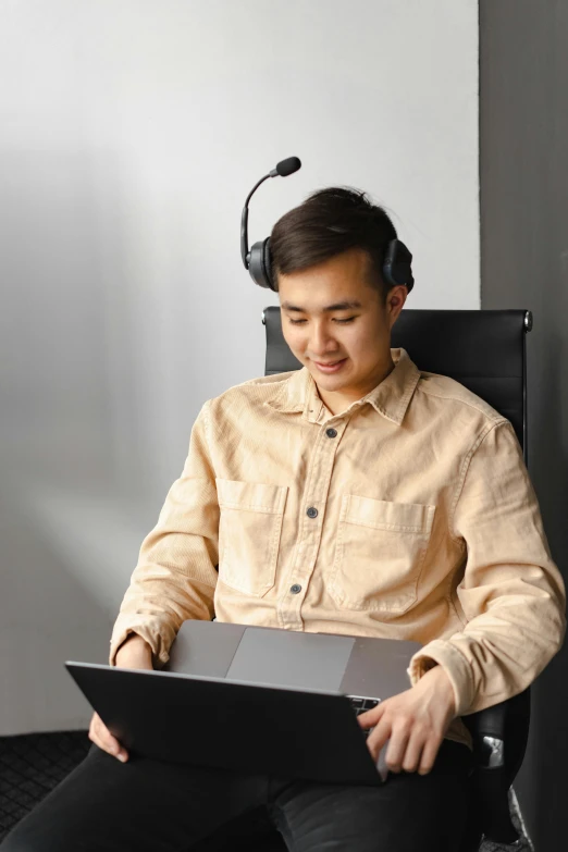 a man sitting in a chair with a laptop and headphones, sitting in front of a microphone, asian human, floating headsets, australian