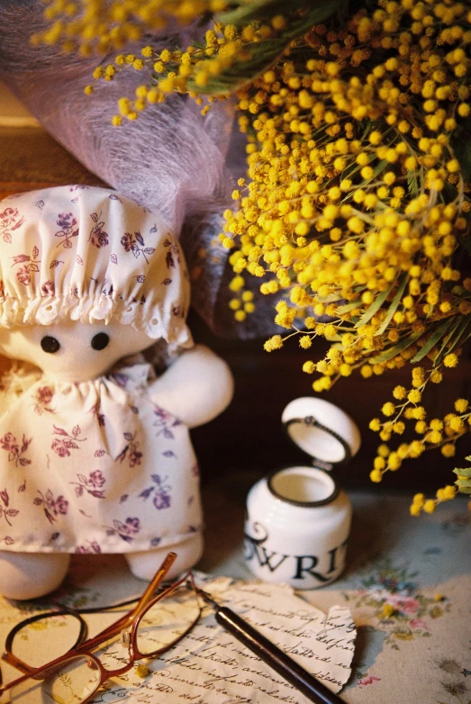 a teddy bear sitting on top of a table next to a vase of flowers, yellow theme, doll faces on a dress, manuka, maison ikkoku