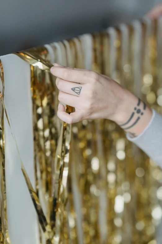 a woman standing next to a radiator in a room, an album cover, by Julia Pishtar, trending on unsplash, happening, holding golden chains, confetti, gold cloth, medium close up shot