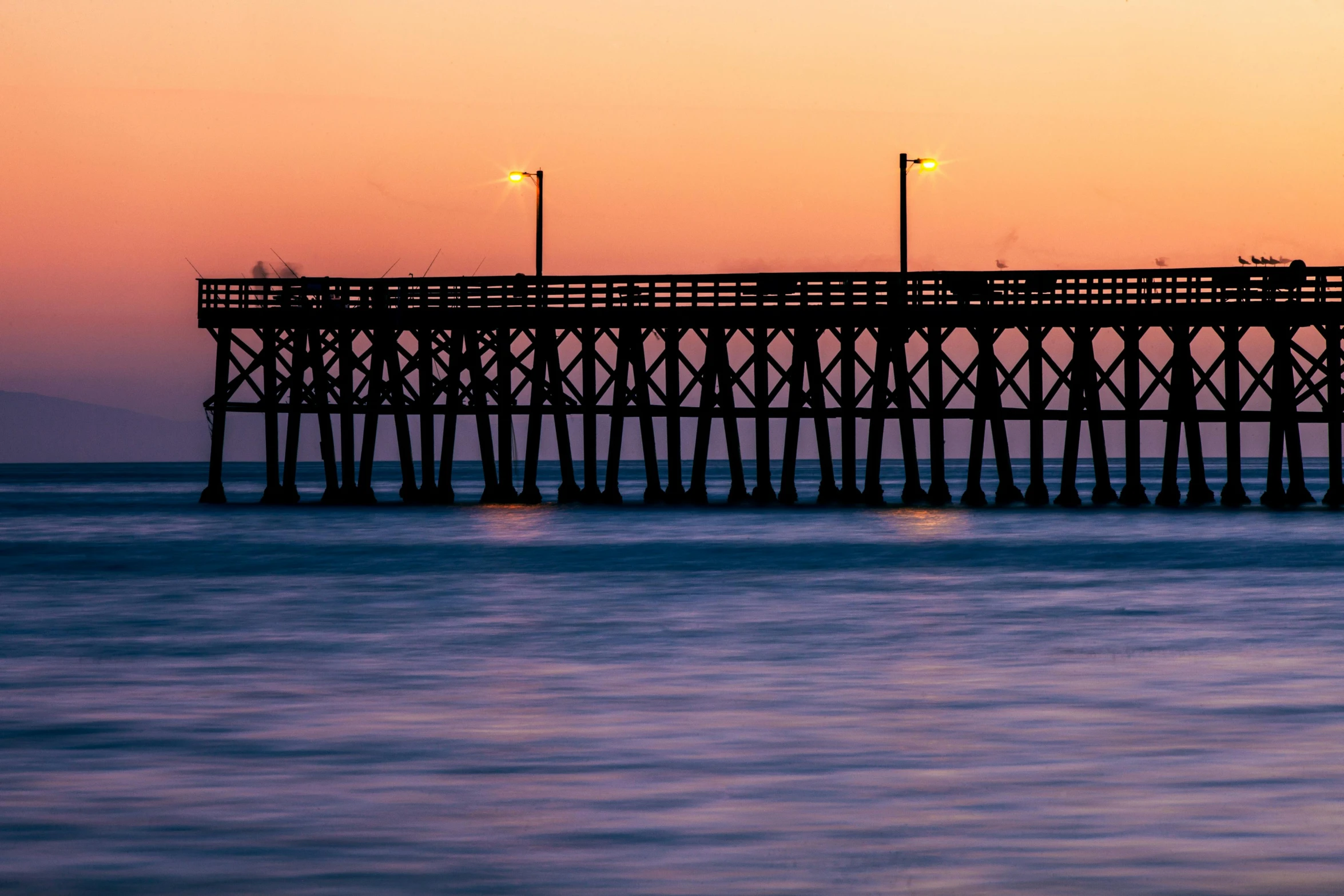 a pier in the middle of the ocean at sunset, by Carey Morris, pexels contest winner, hurufiyya, subtle detailing, brown, hyper color photograph, black