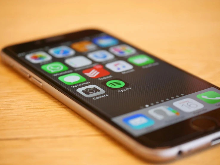 a cell phone sitting on top of a wooden table, pexels, square, apple, multi-dimensional, performing