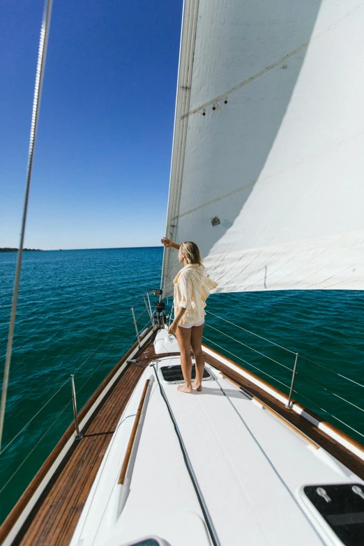 a woman standing on the bow of a sailboat, in australia, clear skies, clean and pristine design, traverse