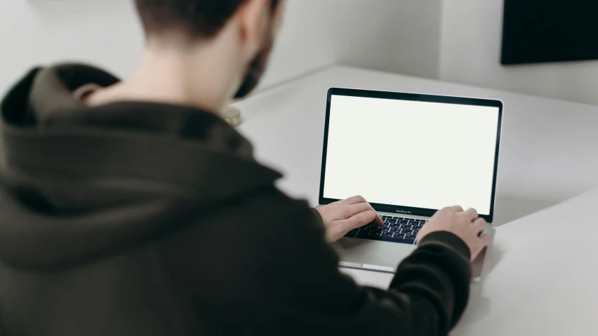 a man sitting at a table using a laptop computer, unsplash, plain background, rectangle, no text!, looking from shoulder