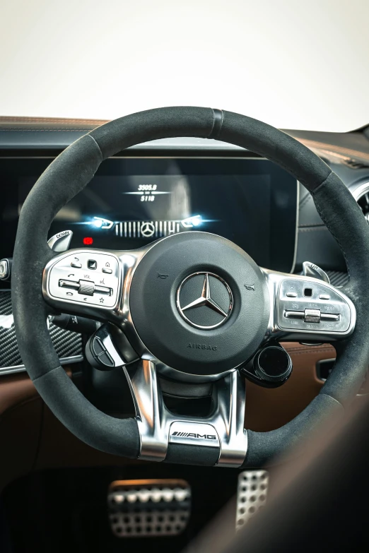 a close up of a steering wheel in a car, mercedes, brown, chrome and carbon, front left speaker