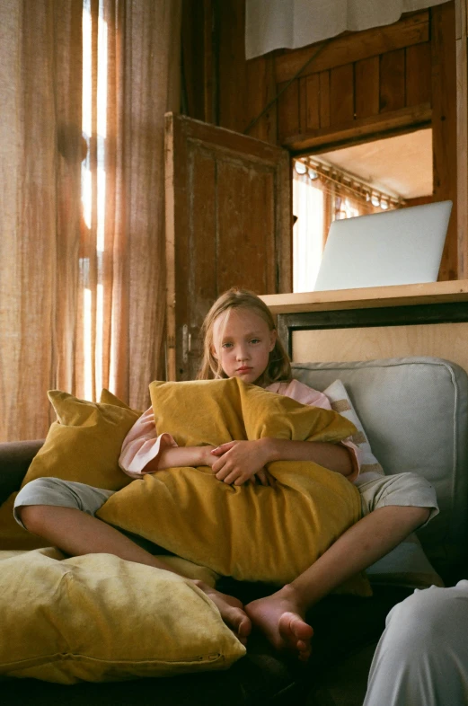 a couple of people that are sitting on a couch, a picture, inspired by Sarah Lucas, unsplash, young girl, yellow, pillows, shot with sony alpha