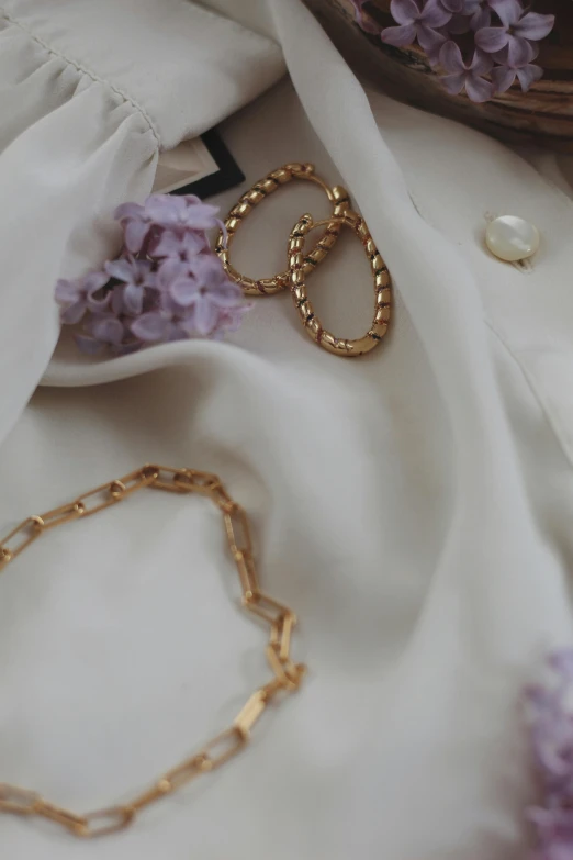 a bunch of jewelry sitting on top of a table, an album cover, by Zofia Stryjenska, trending on pexels, gold chain belt, lilacs, morning detail, detailed clothing