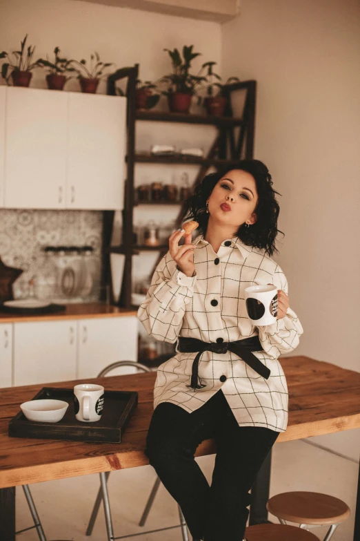 a woman sitting on top of a wooden table, a picture, trending on pexels, arabica style, in a kitchen, pouting, outfit photo