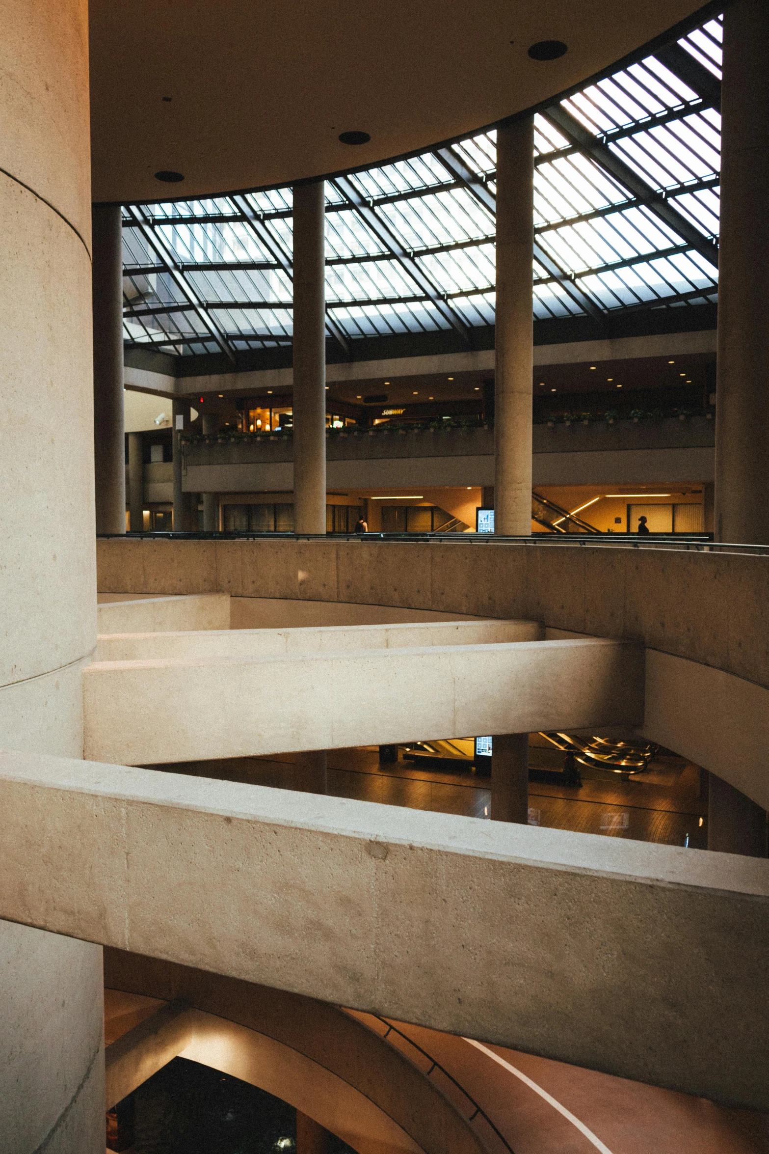 a man riding a skateboard up the side of a ramp, inspired by René Burri, brutalism, interior of a marble dome, set inside of the bank, atrium, lots of glass details