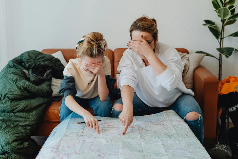 two women sitting on a couch looking at a map, by Emma Andijewska, pexels contest winner, game board, with a kid, wearing dirty travelling clothes, gif